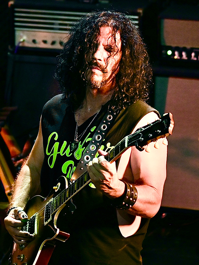 Mike Ruggirello plays a Gibson Les Paul guitar with a Bogner amplifier in the background
